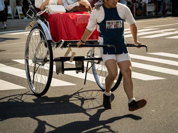 Photography: A rickshaw driver pulling his passengers across the road, Asakusa, Tokyo.