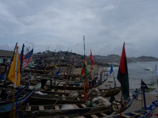 Cape Coast, Ghana: Fishing boats and their flags drawn up on the beach at Cape Coast.
