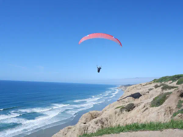 San Diego, California, United States: A paraglider over the sea cliffs at Torrey Pines.