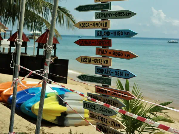 Tioman Island, Malaysia: A signpost on the beach counting the miles home.